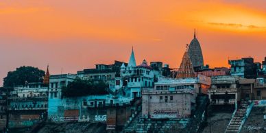 Sunset over riverside buildings with temple spires.