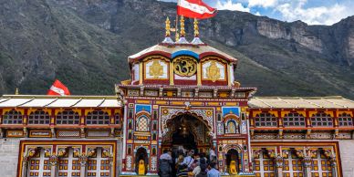 Colorful temple entrance with crowd and mountainous backdrop.