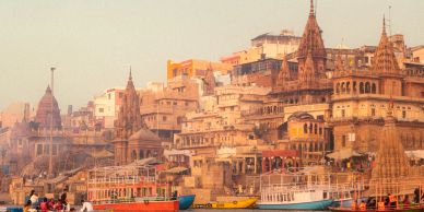 Sunlit historic buildings along a river with boats.