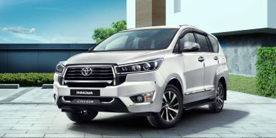 White Toyota Innova Crysta parked outside a modern house.