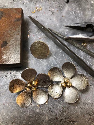 Metal flower crafts with tools on a workbench.