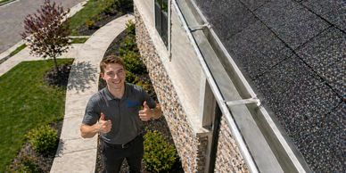 Man gives thumbs up standing by a house with solar panels on the roof.