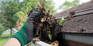 Gloved hand cleaning gutters of debris