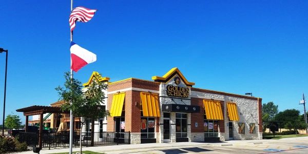 Golden Chick restaurant building with American and Texas flags.