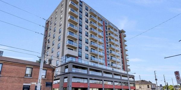Modern multi-story apartment building with balconies under a clear blue sky.