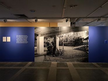 Exhibition wall with a large black-and-white photo and descriptive text on blue panels.