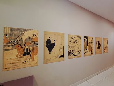 A row of framed art prints displayed on a white gallery wall.