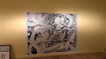 Intricate black and white wall art depicting a reclining figure surrounded by nature and surreal elements.