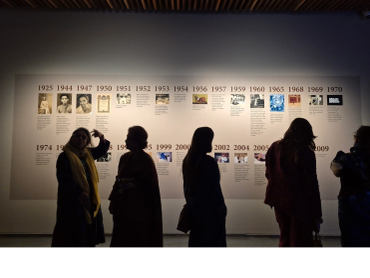 People viewing a historical timeline exhibit in a dimly lit gallery.