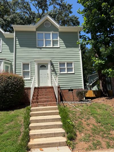 Green two-story house with brick stairs.