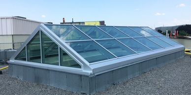 Modern glass skylight on a rooftop against a clear sky.