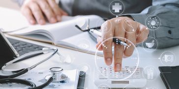 Person using calculator with medical icons overlay, surrounded by stethoscope and documents.