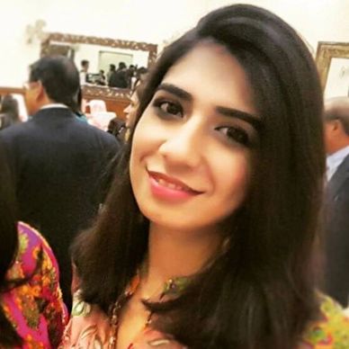 A young woman smiling at a social gathering indoors.