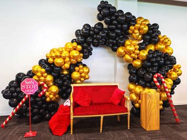 Bold & fun Christmas Photo Booth with balloon garland and Santa seat for charity event.