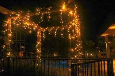 Warm white fairy lights on the gazebo for a poolside party.