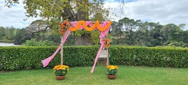 Bright pink and orange wooden wedding arch at Indian wedding at The Riverhead, Auckland.