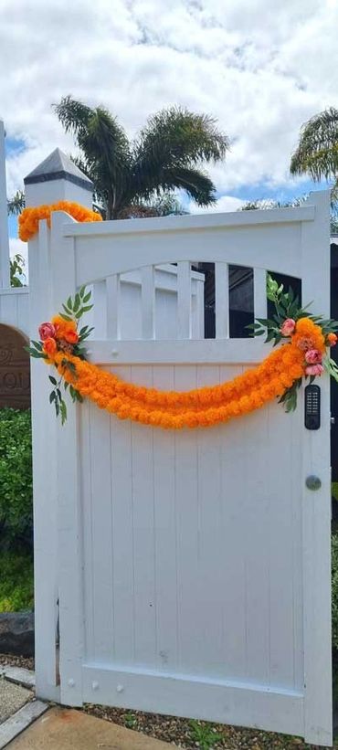 Colourful orange and pink Indian style garland on gate for wedding at The Riverhead in West Auckland