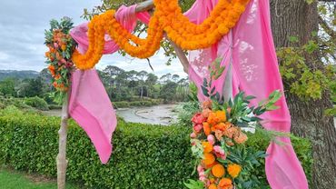 Bright pink and orange wooden wedding arch at Indian wedding at The Riverhead, Auckland.