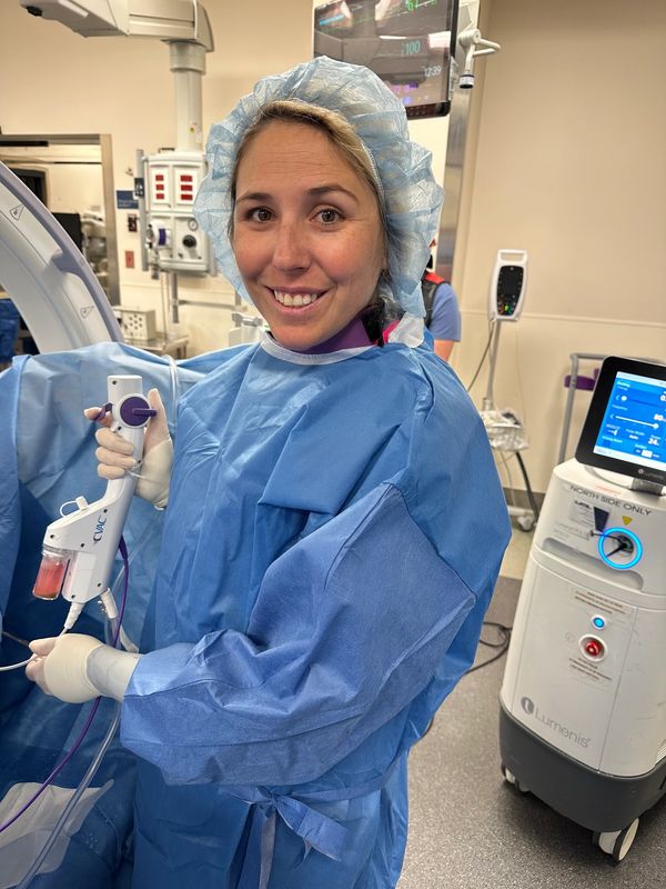 Smiling medical professional in surgical attire holding equipment.