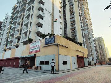 Tall residential building with Indian flag and people nearby.