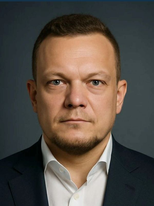 Serious man in formal suit against a dark background.