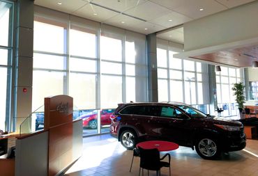 A shiny SUV displayed inside a bright, modern car showroom with large windows.