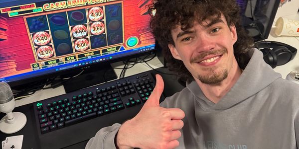 Smiling man gives thumbs up beside computer showing a slot game win.