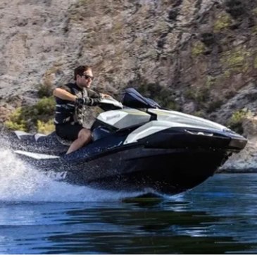 Man riding a jet ski on water near rocky cliffs.