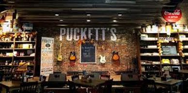 Cozy rustic restaurant interior with guitars and exposed brick wall.