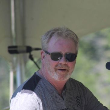 Man wearing sunglasses and beard under a tent.