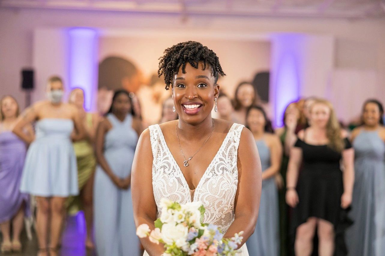 Bride smiling while holding bouquet, preparing to toss it.