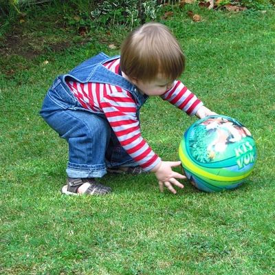 Toddler bending down to pick up ball