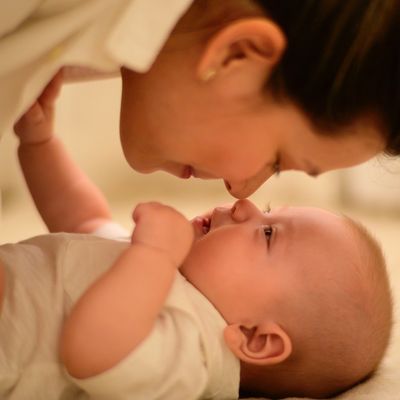 Woman nose to  nose with baby lying on its back