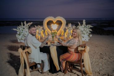 Couple enjoying romantic beach dinner at sunset.