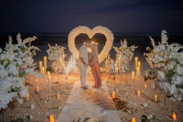 Couple sharing a romantic moment at a beachside heart-shaped wedding setup.