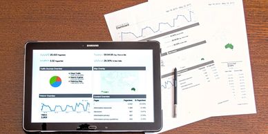 Tablet displaying business analytics alongside printed financial reports and a pen.