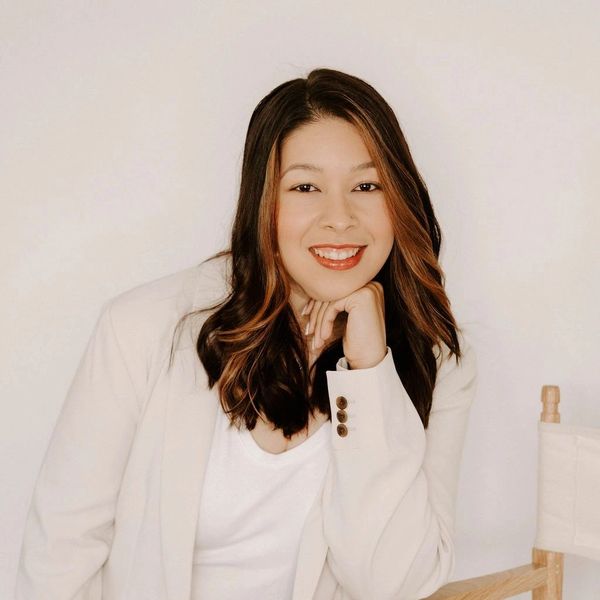 Smiling woman with brown hair wearing a white blazer.