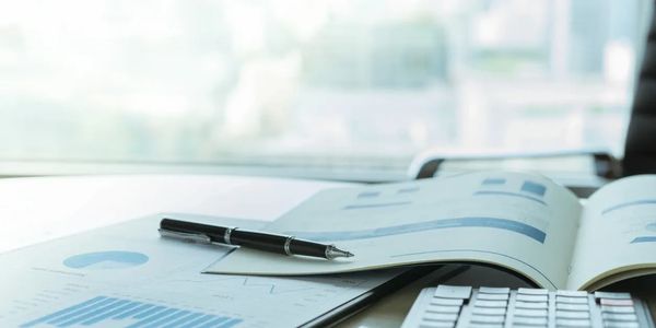 Pen on business report with calculator on desk.
