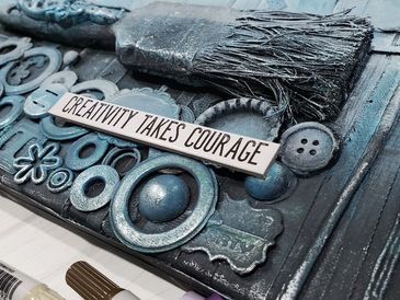 Artistic canvas with textured elements and a sign saying 'Creativity Takes Courage'.