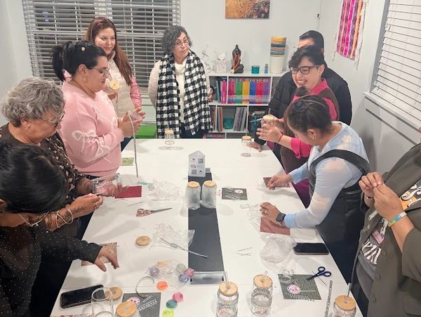 A group of women crafting and socializing around a table indoors.