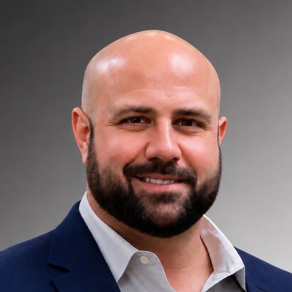 Smiling bald man with beard in suit.