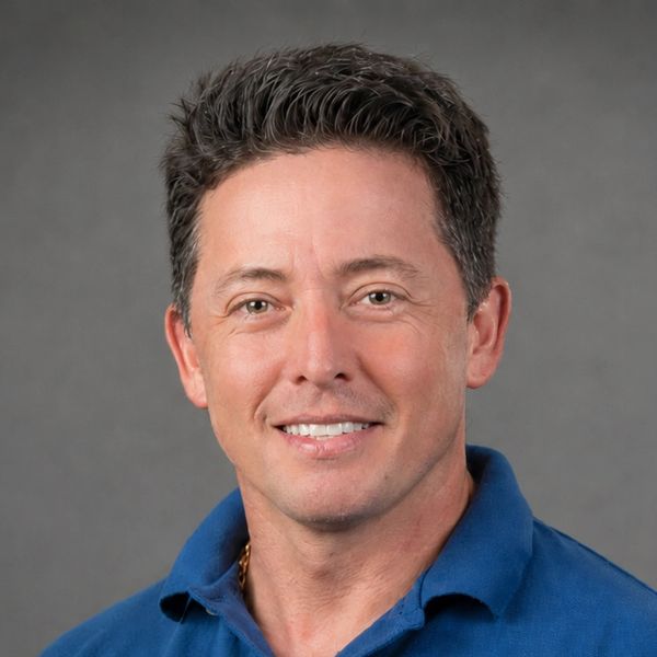 Smiling man with short dark hair in a blue shirt.