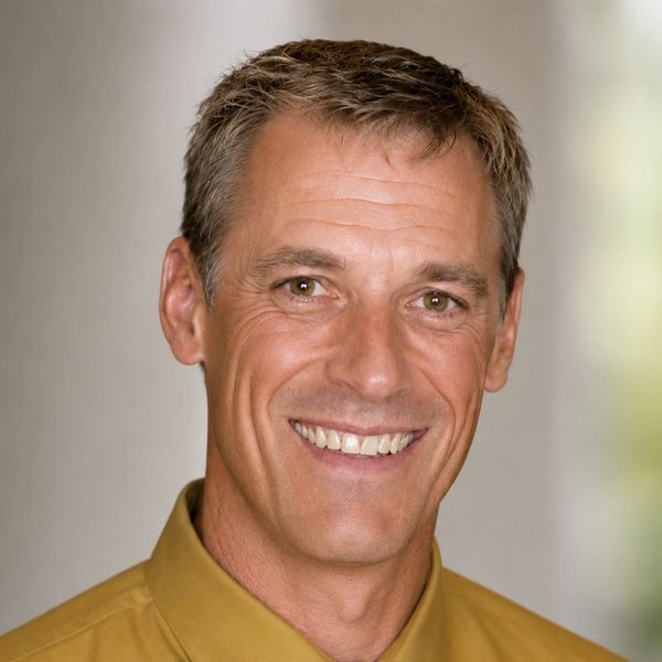 Smiling middle-aged man in a mustard shirt.