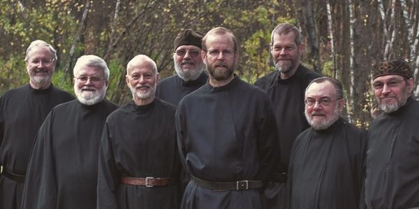 group photo of monks with German Shepherd dog, fall leaves in background