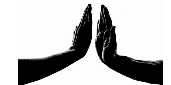 black and white photo of two hands, palms upright mirroring one another but not touching
