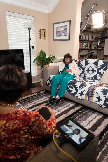 Two women in a living room during a filmed interview setup.