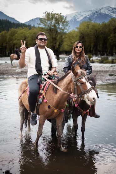 Two people enjoying horse riding in a scenic mountain setting.