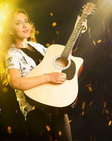 Young woman playing acoustic guitar with warm lighting effects.