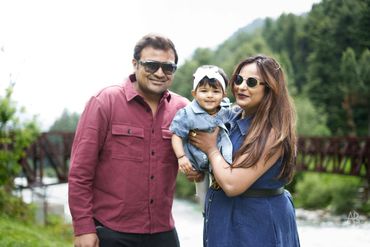 A happy family enjoying time outdoors by a river with greenery around.