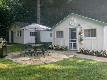 Cozy backyard with two white sheds, patio table, and umbrella.